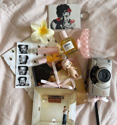 an assortment of personal items laid out on top of a bed next to a camera