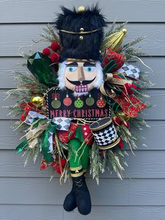 a christmas wreath hanging on the side of a house with a nutcracker figure