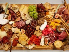 an assortment of cheeses, crackers and meats on a wooden platter