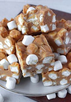 there are marshmallows on top of the brown and white squares in this plate