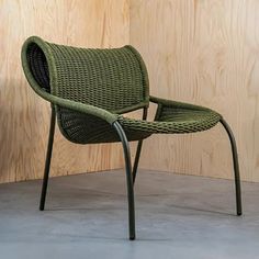 a green chair sitting on top of a cement floor next to a wooden paneled wall