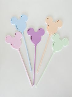 four mickey mouse shaped cake toppers in pastel colors