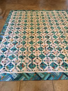 a blue and white quilt sitting on top of a tile floor