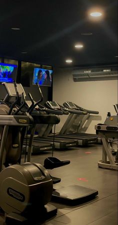 there are many treadmills in the gym with tvs on each one side