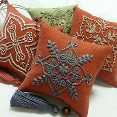 three decorative pillows with tassels on them