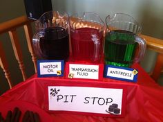 three pitchers of liquid sitting on top of a table next to a sign that says pit stop