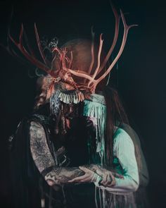 a man with long hair and horns on his head holding a cell phone in front of him