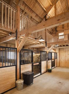 the inside of a horse barn with wooden walls and stalls on either side of it