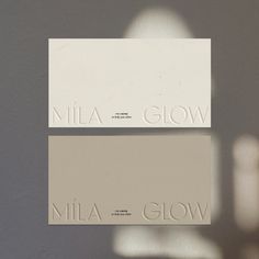 two white business cards with the word nila glow printed on them, against a gray background