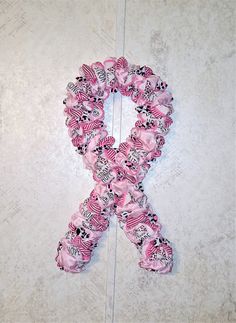 a pink ribbon with black and white designs on it sitting on the ground next to a wall