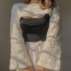 a woman wearing a white crochet sweater with open shoulders