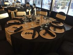 the table is set with black and white plates, silverware, and wine glasses