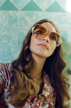 a woman with sunglasses on her face is taking a selfie in front of a tiled wall