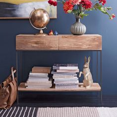 a wooden table topped with lots of books next to a vase filled with red flowers