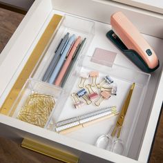 an open drawer with pens, scissors and other office supplies