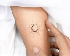 a person with a small sun tattoo on their arm