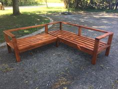 a wooden bench sitting on top of a gravel road next to a tree filled park