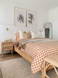 a bed with orange and white checkered bedspread in a bedroom next to two pictures on the wall