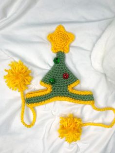 a crocheted christmas tree hat and matching pom - poms on a white sheet