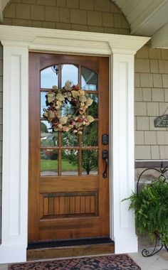 the front door is decorated with wreaths and potted plants on the porch area