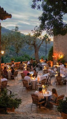 an outdoor dining area with tables, chairs and people sitting at the table eating outside