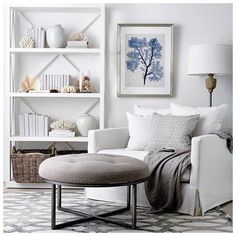 a living room filled with white furniture and bookshelves next to a wall mounted book shelf