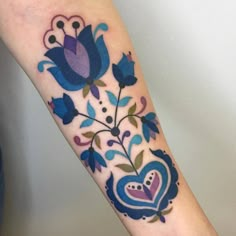 a blue flower and heart tattoo on the arm