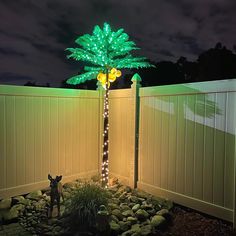 a lighted palm tree next to a fence