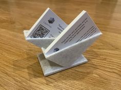 two white business cards sitting on top of a wooden table with qr code attached to them