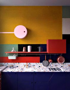 a kitchen with multicolored walls and cabinets in the center, along with a sink