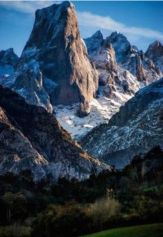 the mountains are covered in snow and green grass