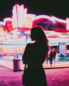 A young woman is standing in front of a carnival fair. Backlit by pink and red lights. Carnival Aesthetic Photoshoot, Euphoria Carnival Aesthetic, Fair Photography Night, Funfair Aesthetic Night, Funfair Photoshoot, County Fair Photoshoot