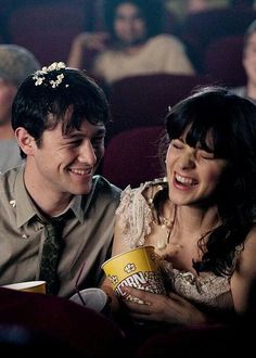 a man and woman sitting next to each other in front of a movie theater audience