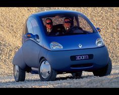 two men are driving a small car on the beach