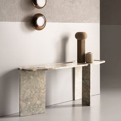 a marble table with two candles on it next to a wall mounted mirror and candle holder