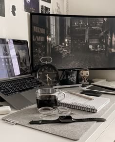 a laptop computer sitting on top of a desk next to a cup of coffee and pen