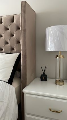 a nightstand with a lamp on top of it next to a night stand and bed