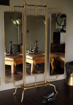 three mirrors sitting on top of a wooden floor in front of a wall mounted mirror