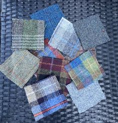 a pile of different colored squares sitting on top of a woven tablecloth covered in fabric