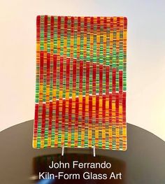 a glass art piece sitting on top of a table next to a sign that says, john ferando kiln - form glass art