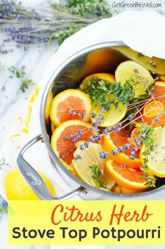 a pot filled with oranges and lavender on top of a white cloth next to lemon wedges