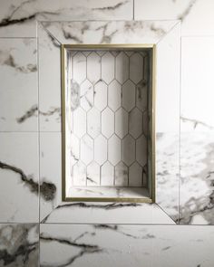 a bathroom with marble walls and flooring, an open window in the wall that has hexagonal tiles on it