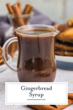 a cup of gingerbread syrup with cinnamon sticks in the background