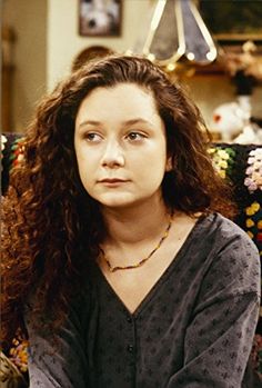 a woman with long curly hair sitting on a couch