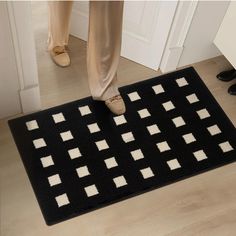 a person standing on the floor in front of a black and white rug with squares