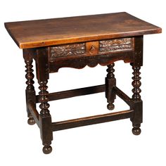 an old wooden table with two drawers on one side and carved wood at the top