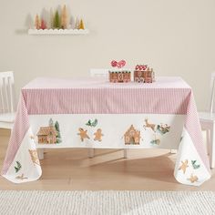 a christmas table with gingerbread cookies and candy on the tablecloth, next to a white chair