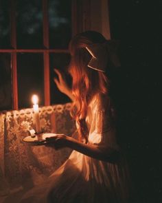 a woman sitting on a couch holding a plate with a lit candle in front of her