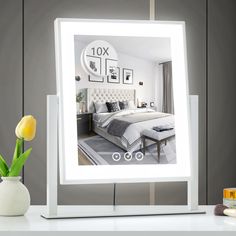 a white lighted mirror sitting on top of a table next to a yellow tulip