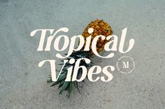 a pineapple sitting on top of a sandy beach next to the words tropical vibes